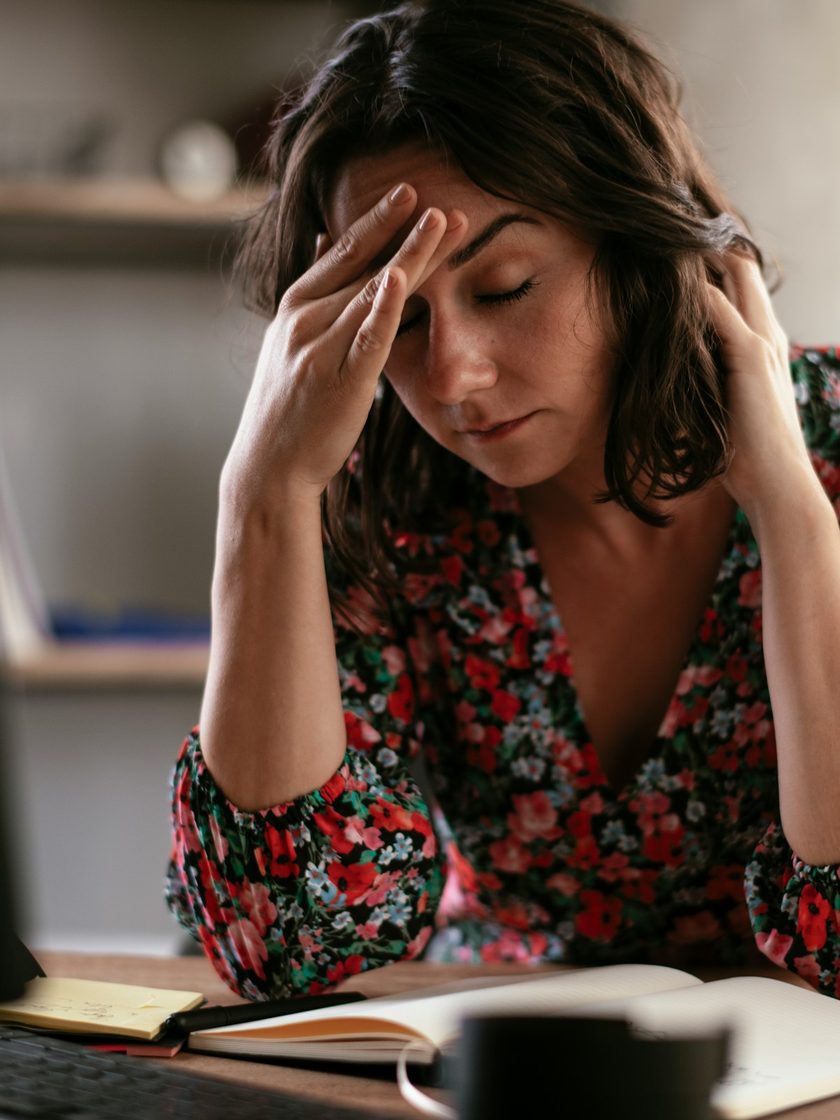 A frustrated professional at her desk, worn down by paperwork